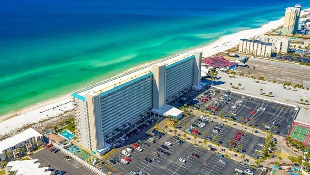 Een hotel met een ruime parkeerplaats en uitzicht op het strand.