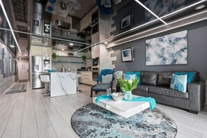 A modern living room with a grey sofa, a coffee table, and a kitchen in the background. - The Summit 231 - Corner of Paradise (Panama City)