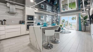 A modern kitchen with a central island, bar stools, and a dining area with a view. - The Summit 231 - Corner of Paradise (Panama City)