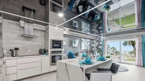 A modern kitchen with built-in appliances, a dining area with a bar stool, and a balcony with a view. - The Summit 231 - Corner of Paradise (Panama City)