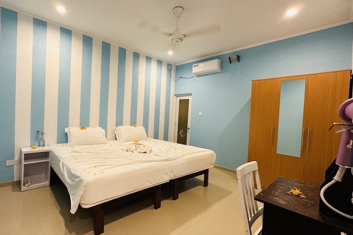 A hotel room with a bed, bedside table, and a wardrobe.
