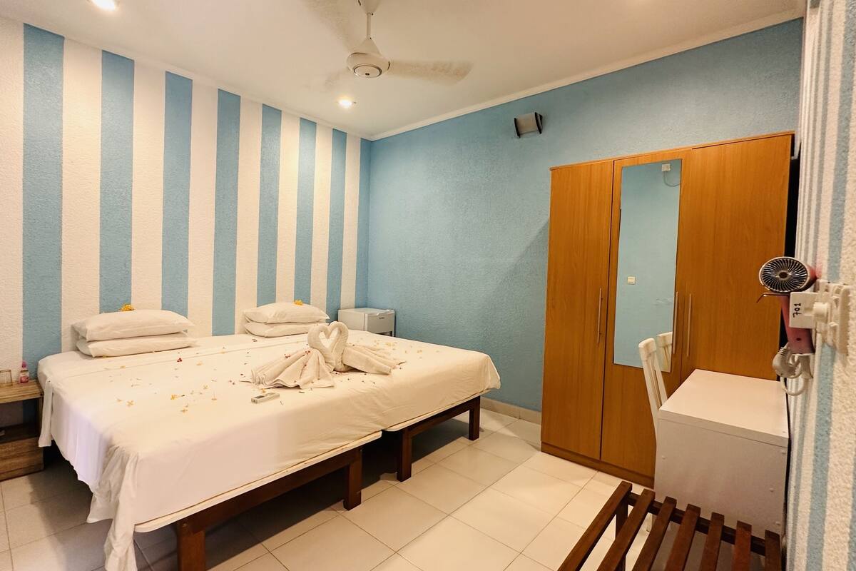 A bedroom with a bed, bedside tables, a wardrobe, and a bathroom with a sink and mirror.