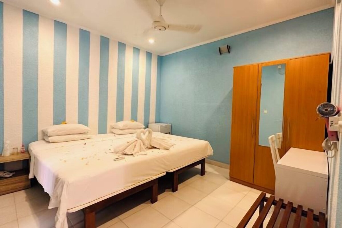 A hotel room with a bed, bedside table, and a wardrobe.