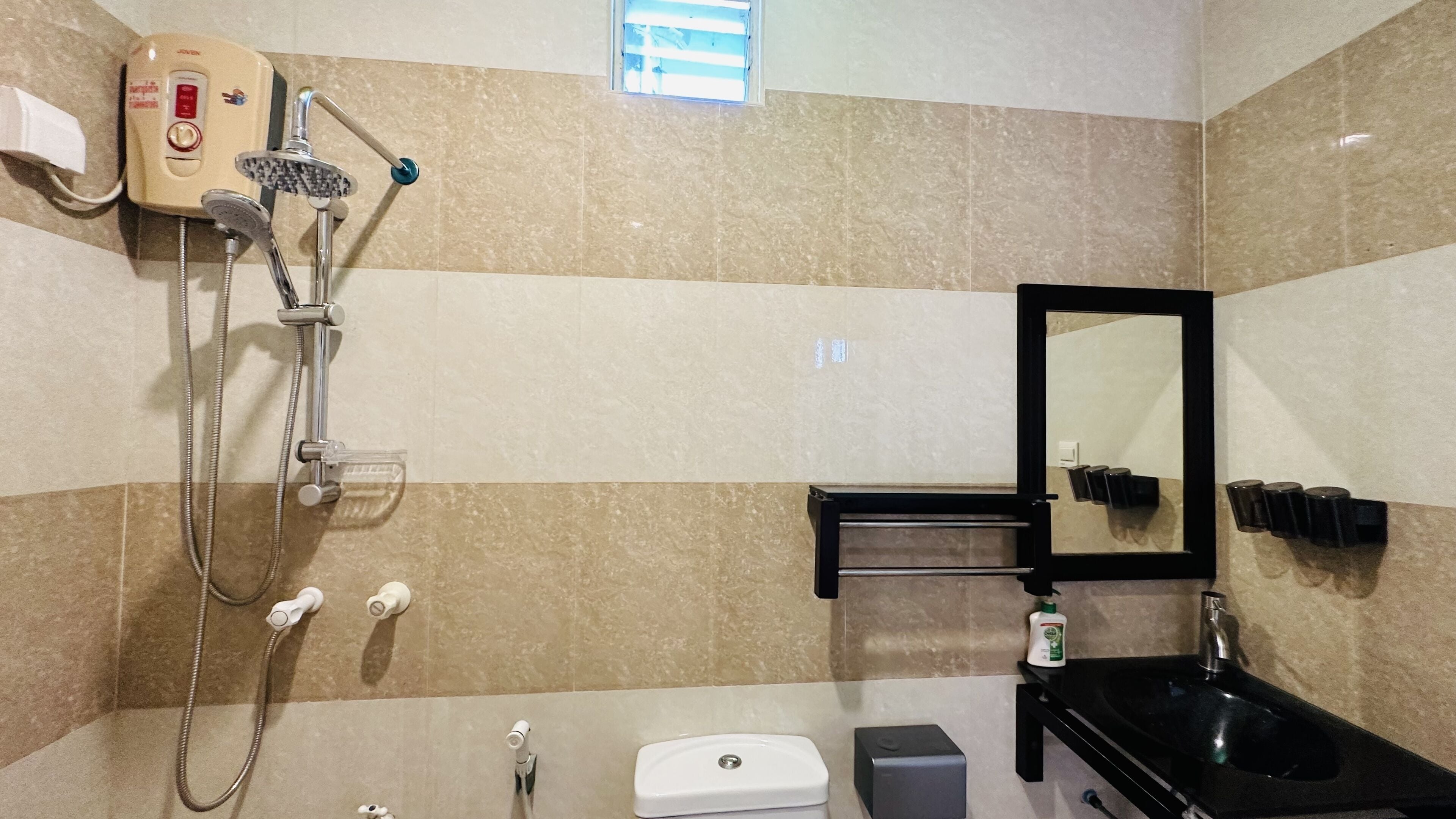 A bathroom with a shower, a sink, a mirror, and a towel rack.