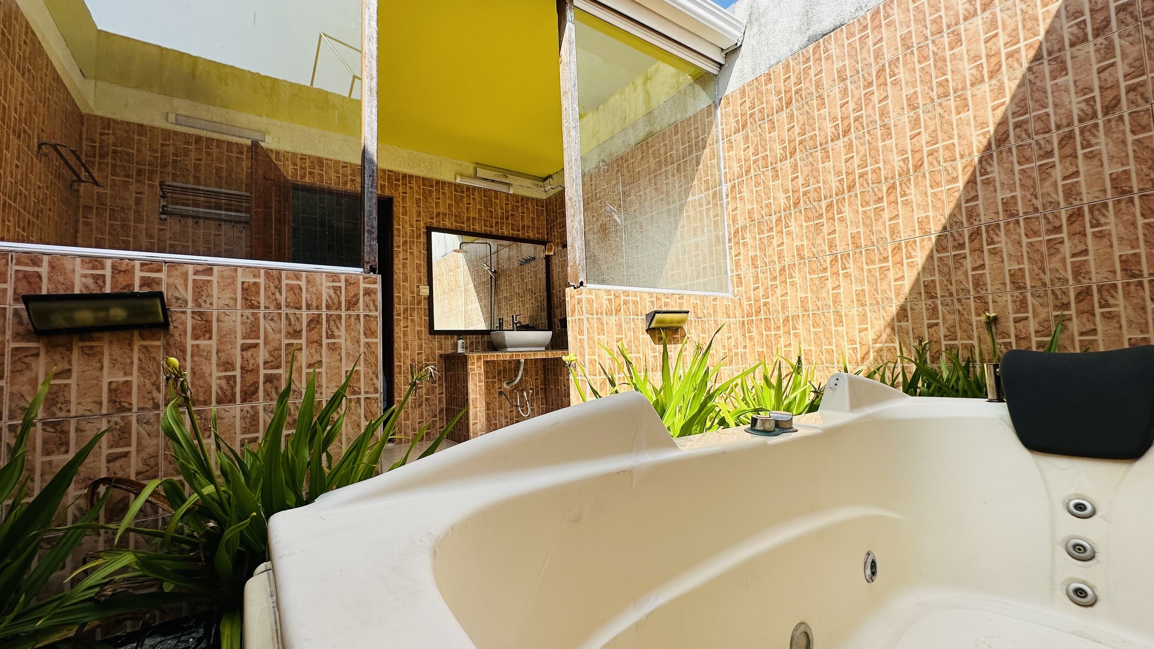 Un baño con bañera, espejo y paredes con azulejos.