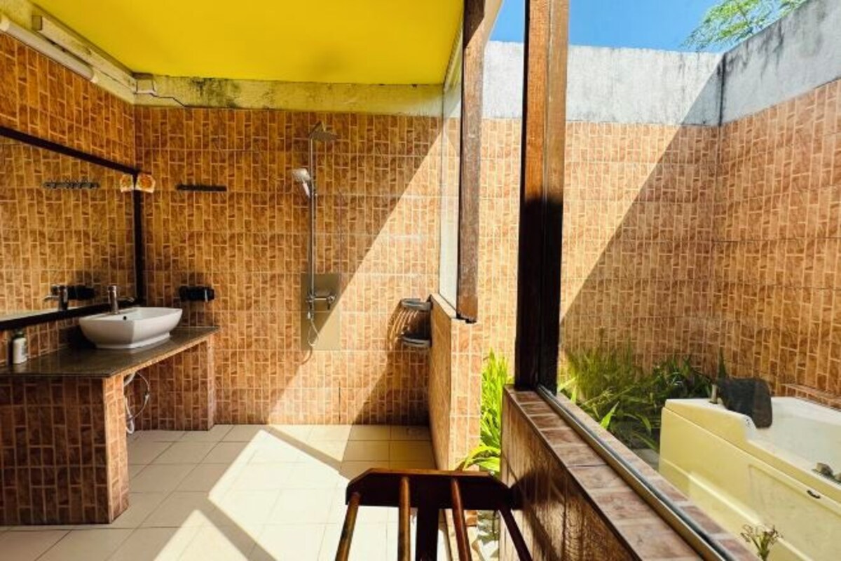 A bathroom with a yellow ceiling, a sink, a shower, and a bathtub.