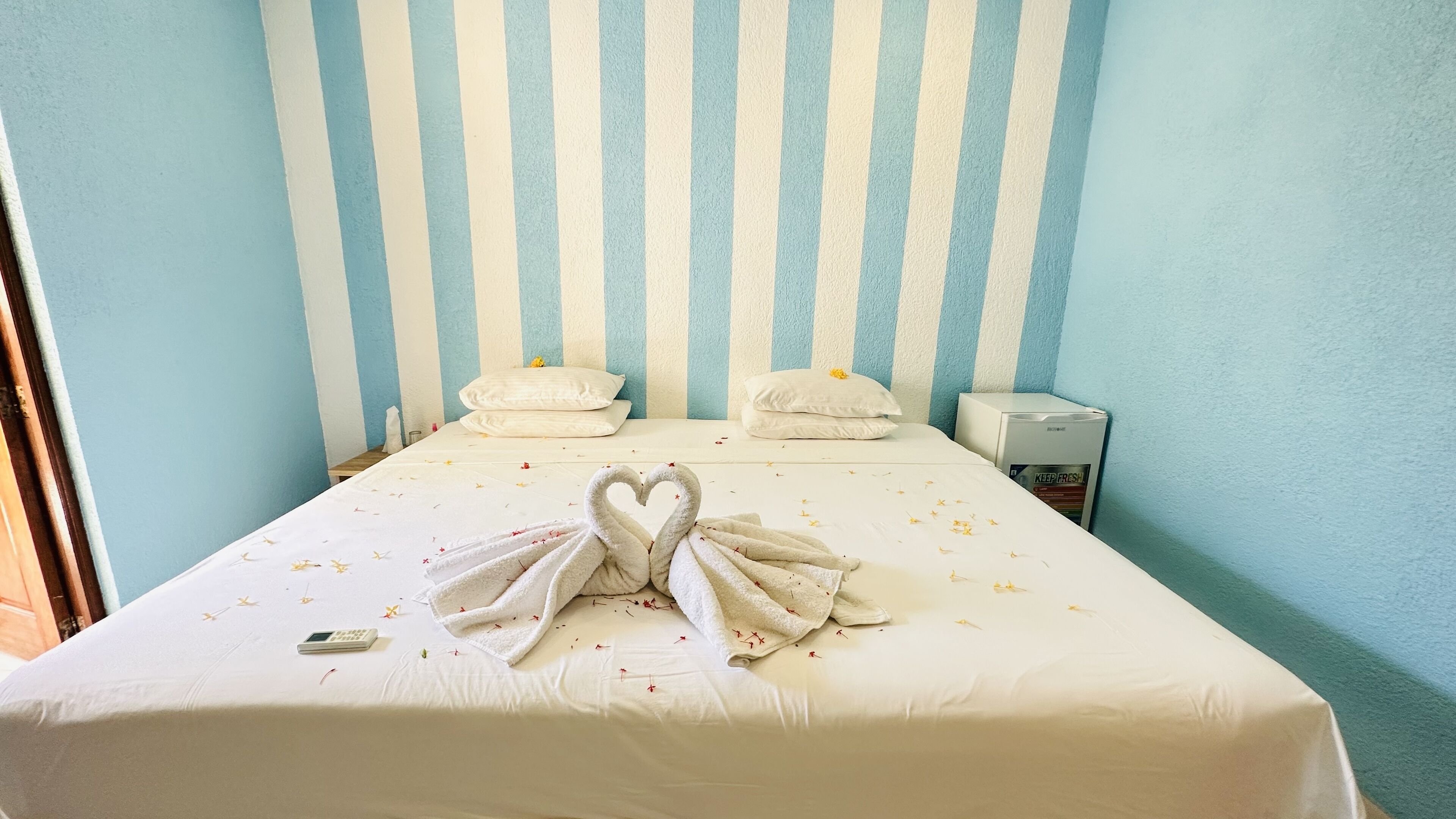 Une chambre d’hôtel comprenant un lit, deux oreillers, une table de chevet et un petit appareil électroménager.