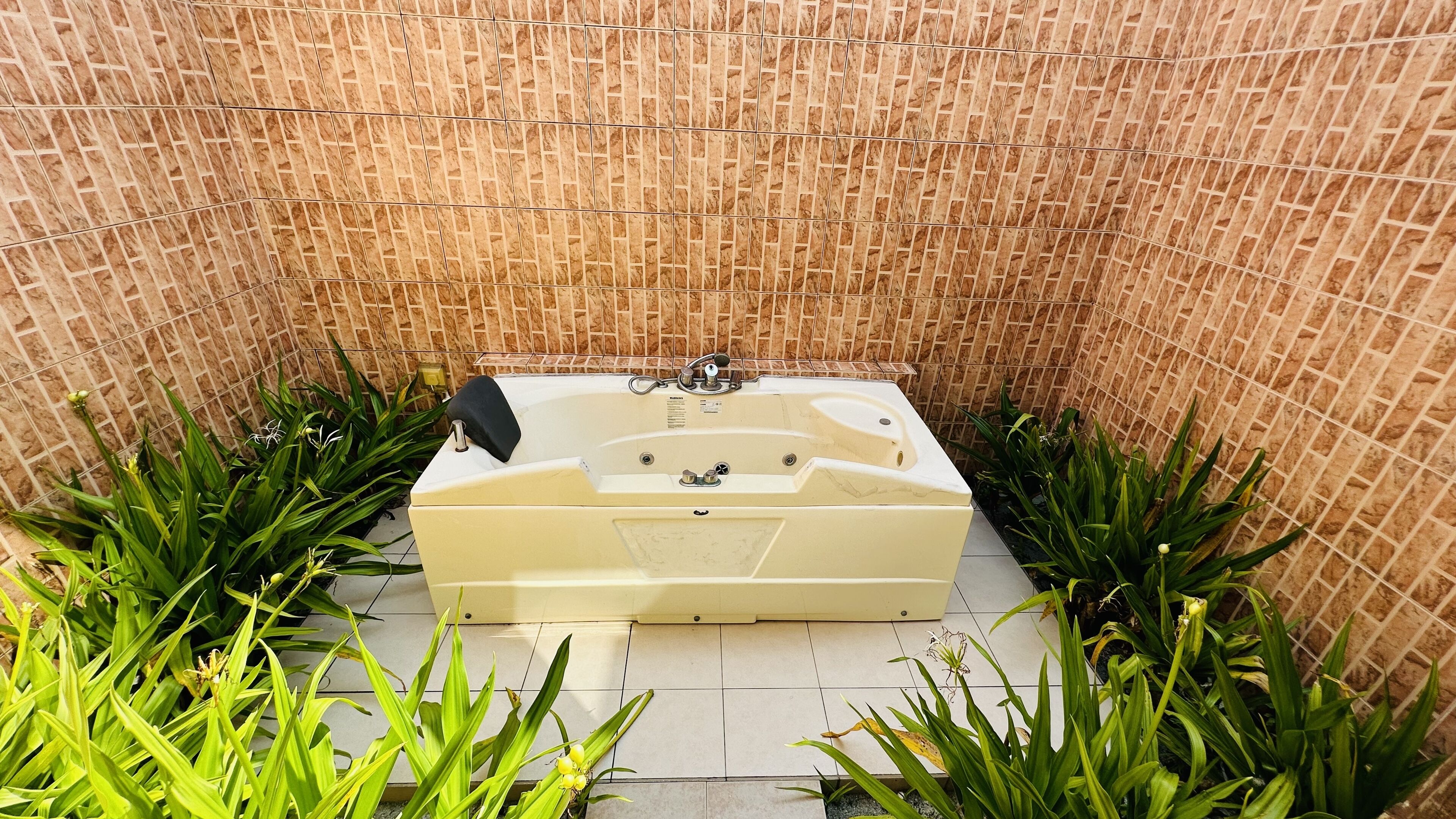 A spa-like bathroom with a bathtub, tiled walls, and green plants.