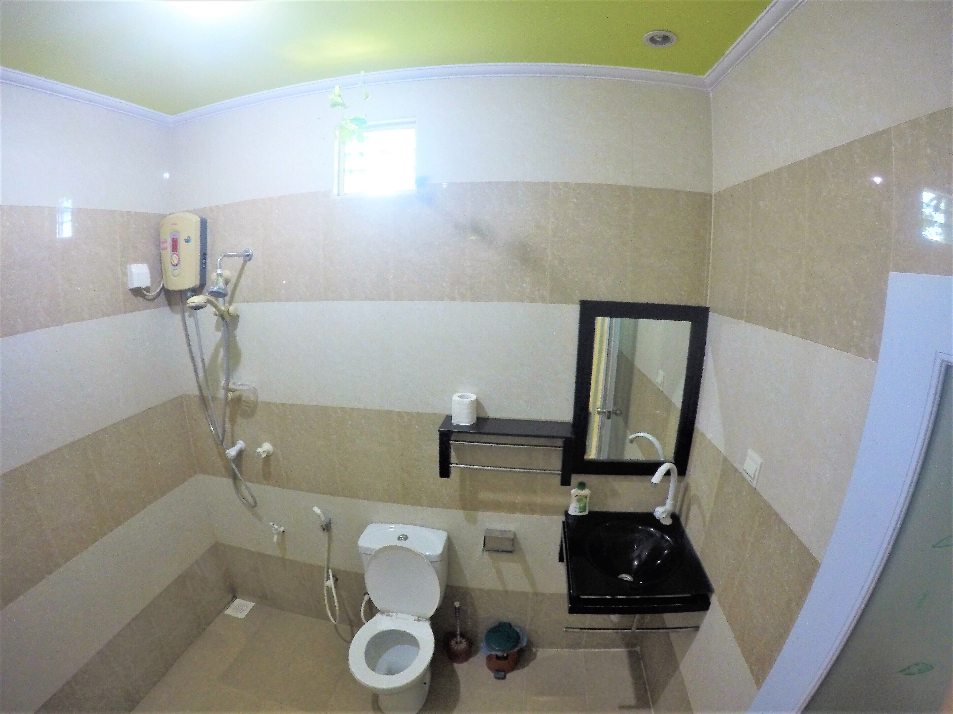 A bathroom with a toilet, sink, mirror, and shower.
