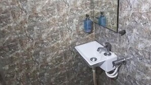 Une salle de bain avec un mur en marbre, un lavabo blanc et un miroir.