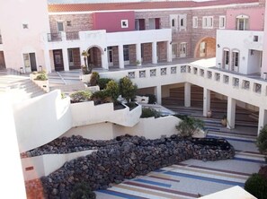A courtyard with a central stone feature, surrounded by buildings with balconies and windows.