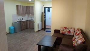 A living area with a sofa, a coffee table, and a kitchen in the background. - Good apartment 300 m from Black sea (Batumi)
