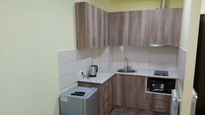 A compact kitchen with wooden cabinets, a built-in microwave, a sink, and a small refrigerator. - Good apartment 300 m from Black sea (Batumi)