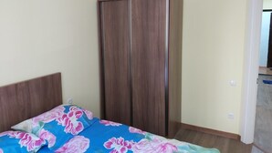 A bedroom with a bed, a wardrobe, and a door leading to another room. - Good apartment 300 m from Black sea (Batumi)