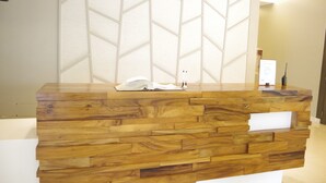 A reception desk with a wooden finish and a geometric patterned wall behind it. - Avida Towers Riala (Cebu City)