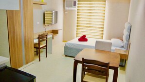 A compact room with a bed, a desk, a chair, a TV, and an air conditioning unit. - Avida Towers Riala (Cebu City)
