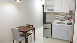 A compact kitchen with a dining table and chairs, a refrigerator, and a sink. - Avida Towers Riala (Cebu City)