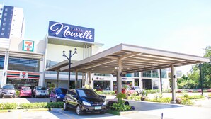 A 7-Eleven convenience store adjacent to a building with a 'Novelle' sign. - Spianada Residences (Cebu City)