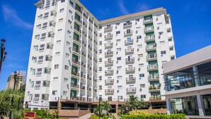 A multi-story residential building with balconies, a parking area, and a modern glass structure adjacent to it. - Spianada Residences (Cebu City)