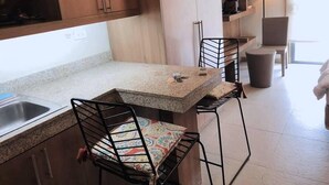 A compact kitchen with a granite countertop, two chairs, a small table, and a sink. - City Suites Ramos Tower (Cebu City)