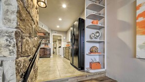 Una cocina moderna con refrigerador negro, piso de madera y pared de acento de piedra.