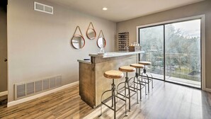 Una cocina moderna con barra, taburetes de madera y grandes ventanales con vistas al exterior.