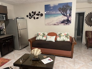 Cozy living space with a kitchenette, dining table, and sofa, perfect for relaxing.