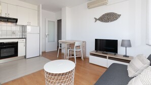 Une cuisine moderne avec des meubles blancs, un four encastré et un coin repas comprenant une table et des chaises.