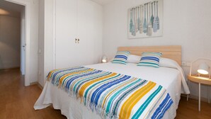 Une chambre à coucher avec un lit, une table de chevet, une lampe fixée au mur et une porte.