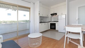 Une cuisine moderne avec des meubles blancs, un four encastré et un coin repas comprenant une table et des chaises.