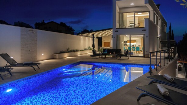 A modern two-story house with a swimming pool, outdoor seating, and a well-lit interior. - Newly Built 5 Star Luxury Villa Bondi for 8 people Next to Beautiful Beach (Supetar)