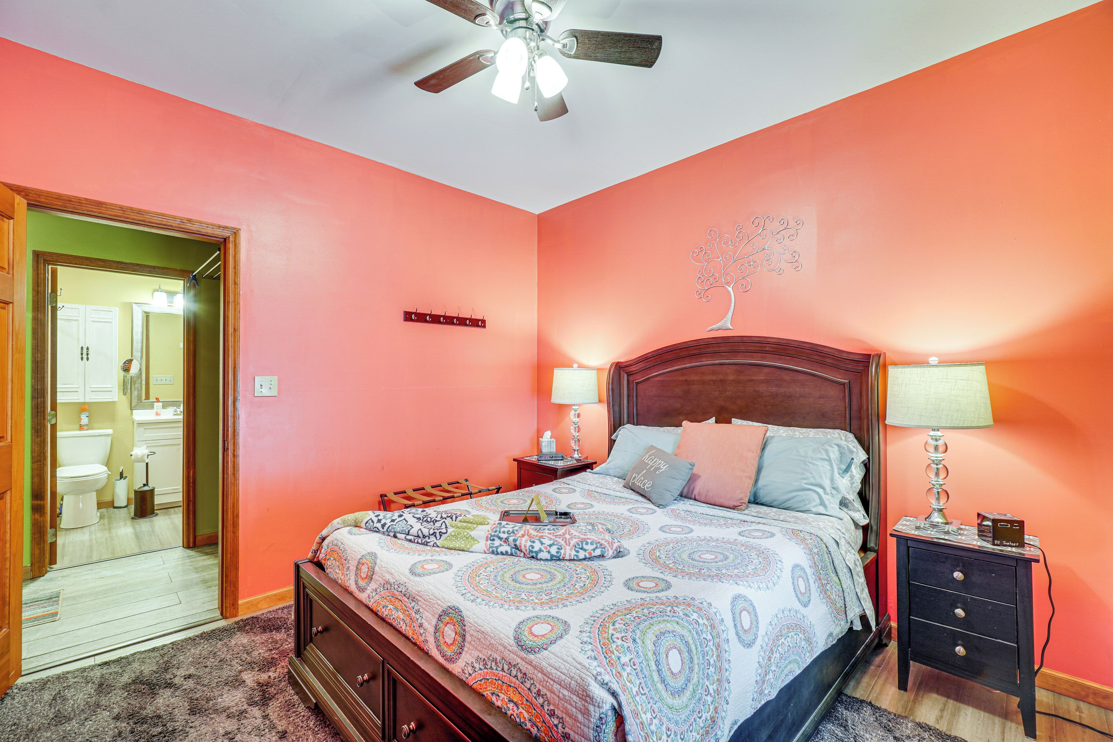 A bedroom with a bed, nightstands, a ceiling fan, and a bathroom visible through an open door.