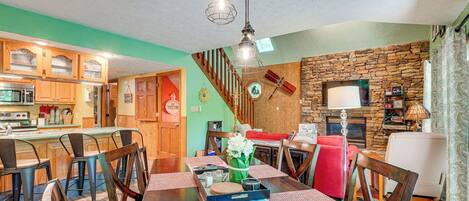 A dining area with a wooden table, chairs, and a kitchen in the background.
