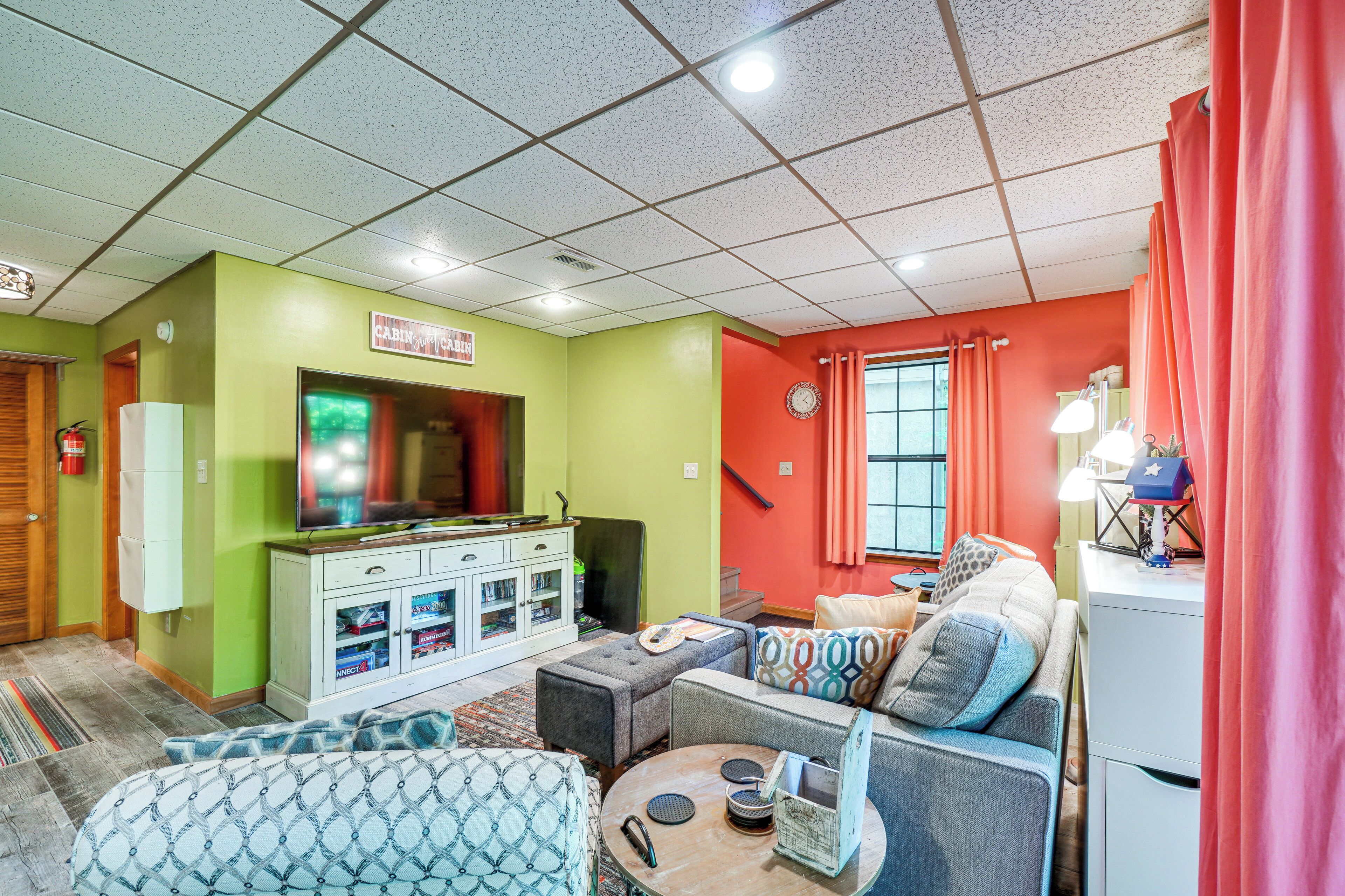 Een woonkamer met een televisie, bank, voetenbankje en een kast met opbergruimte.
