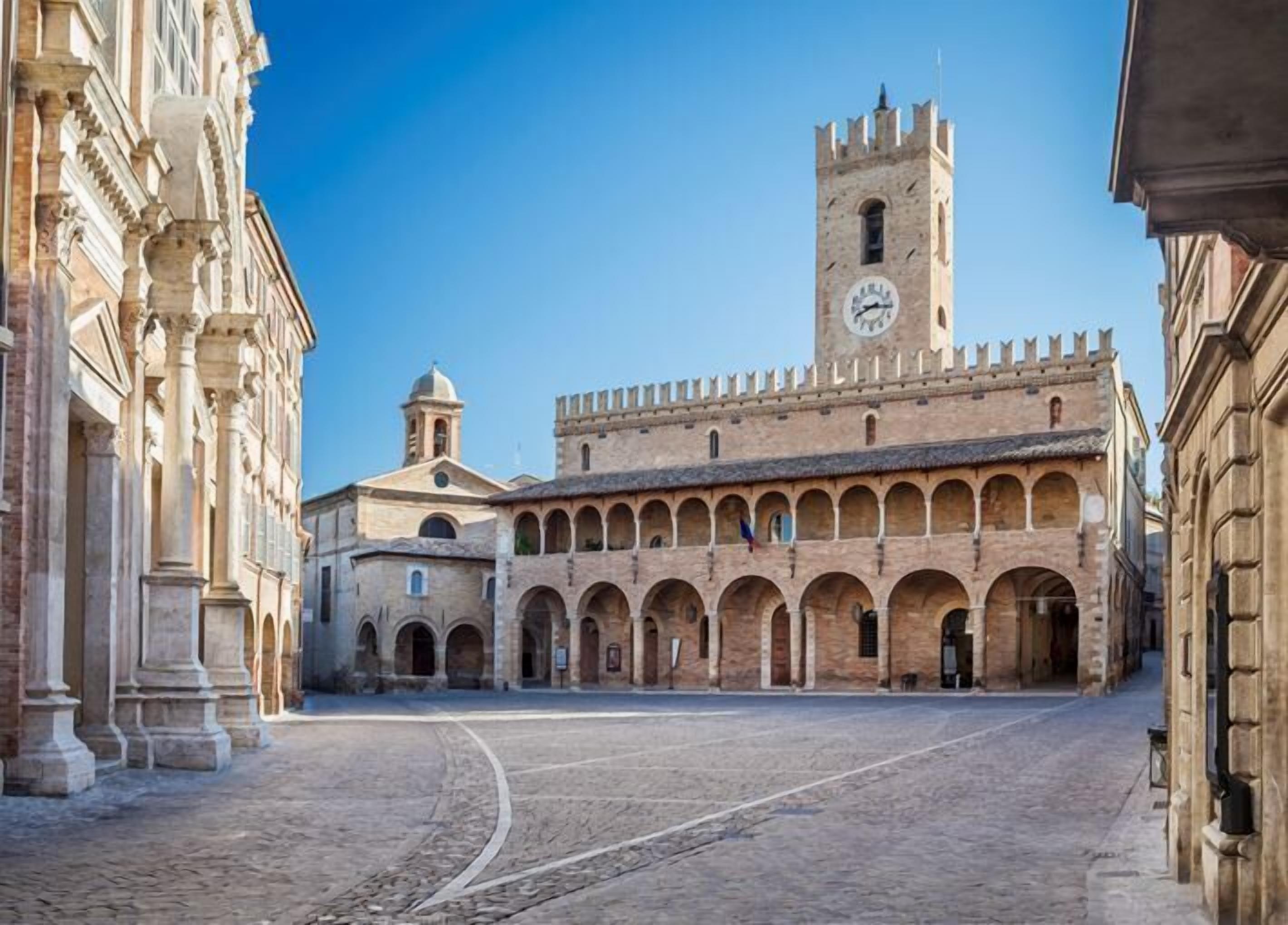 Un edificio storico con una torre dell'orologio e porticati ad arco.