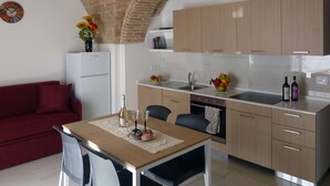Una cocina compacta con comedor, refrigerador, pileta y horno empotrado.