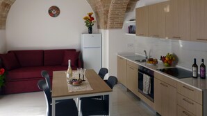 Una cocina moderna con comedor, que presenta un arco de ladrillo, un refrigerador, armarios de madera y un sofá rojo.