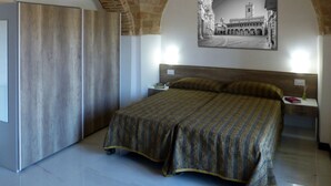 Un dormitorio con una cama, una mesita de noche, un cuadro colgado en la pared y un armario de madera.