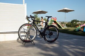 Una bicicleta estacionada cerca de un tobogán y dos sombrillas.