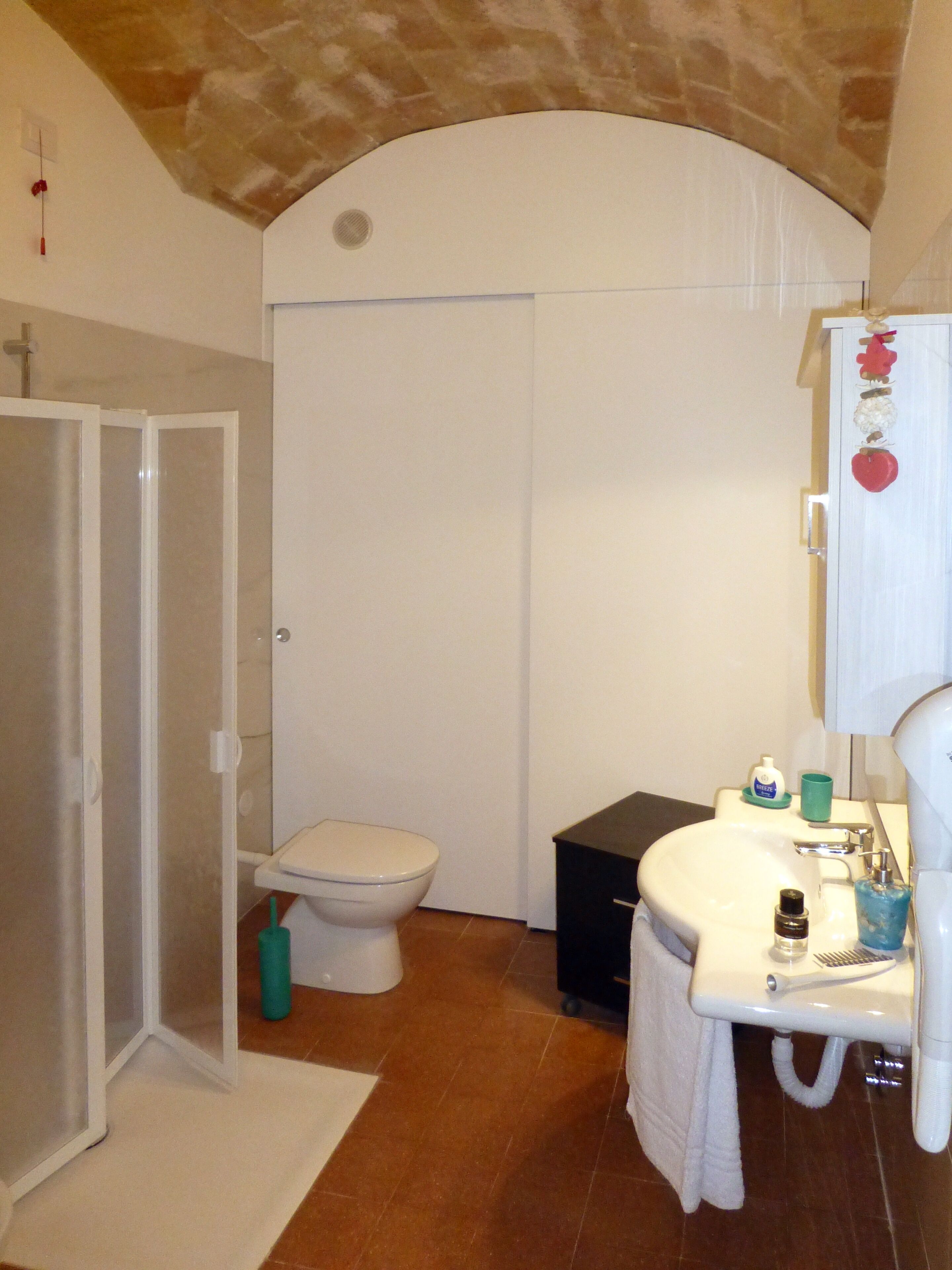 A bathroom with a toilet, sink, and shower area.