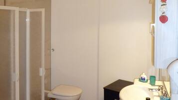 A bathroom with a toilet, sink, and shower area.