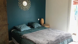 Une chambre à coucher comprenant un lit, une table de chevet, un miroir décoratif et un panier en osier.