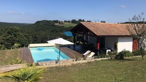 Une maison avec une piscine, un hamac et une vue sur les collines environnantes.