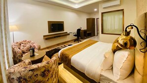 Une chambre d’hôtel équipée d’un lit, d’un bureau, d’une chaise, d’une télévision et d’un ventilateur de plafond.