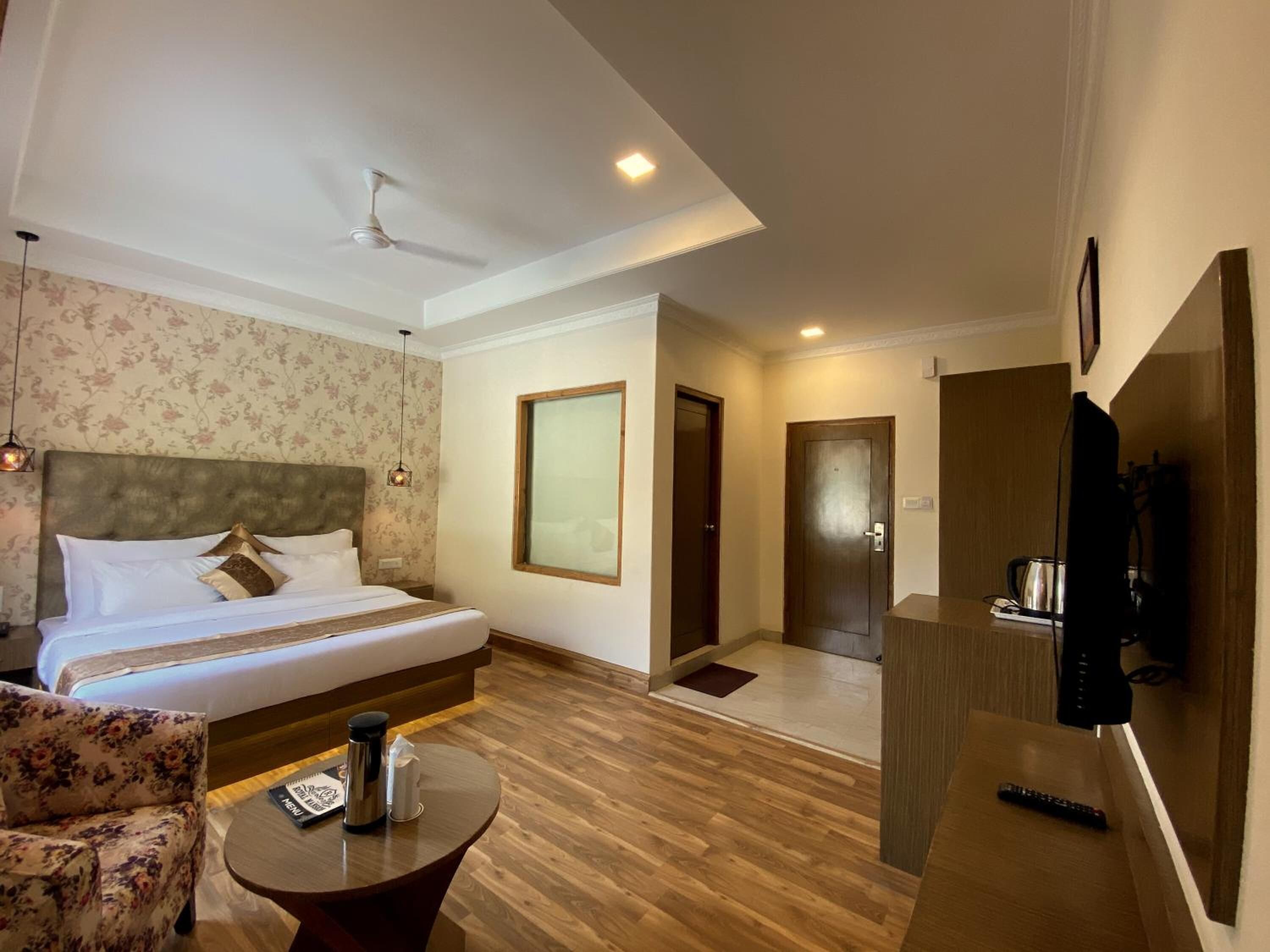 Una habitación de hotel con una cama, una mesita redonda con un control remoto, una cafetera y un televisor.