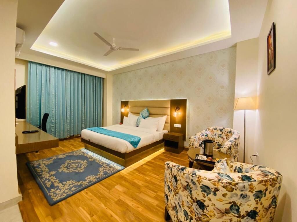 A hotel room with a bed, a desk, a chair, a coffee table, and a ceiling fan.