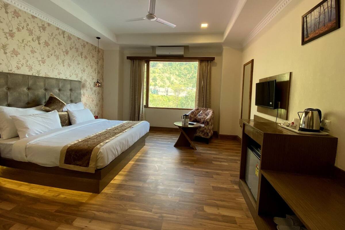 Habitación de hotel con cama, televisión, cafetera y vista a zonas verdes.