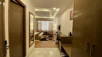 A hotel room with a bed, a desk, a chair, a TV, and a wardrobe.