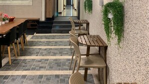 A restaurant with a stone-tiled floor, wooden tables and chairs, hanging plants, and pendant lighting. - 910 Hostel (Yuli)