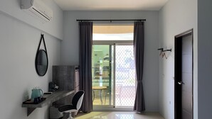 A modern room with a built-in desk, a chair, a large window with curtains, and a door. - 910 Hostel (Yuli)